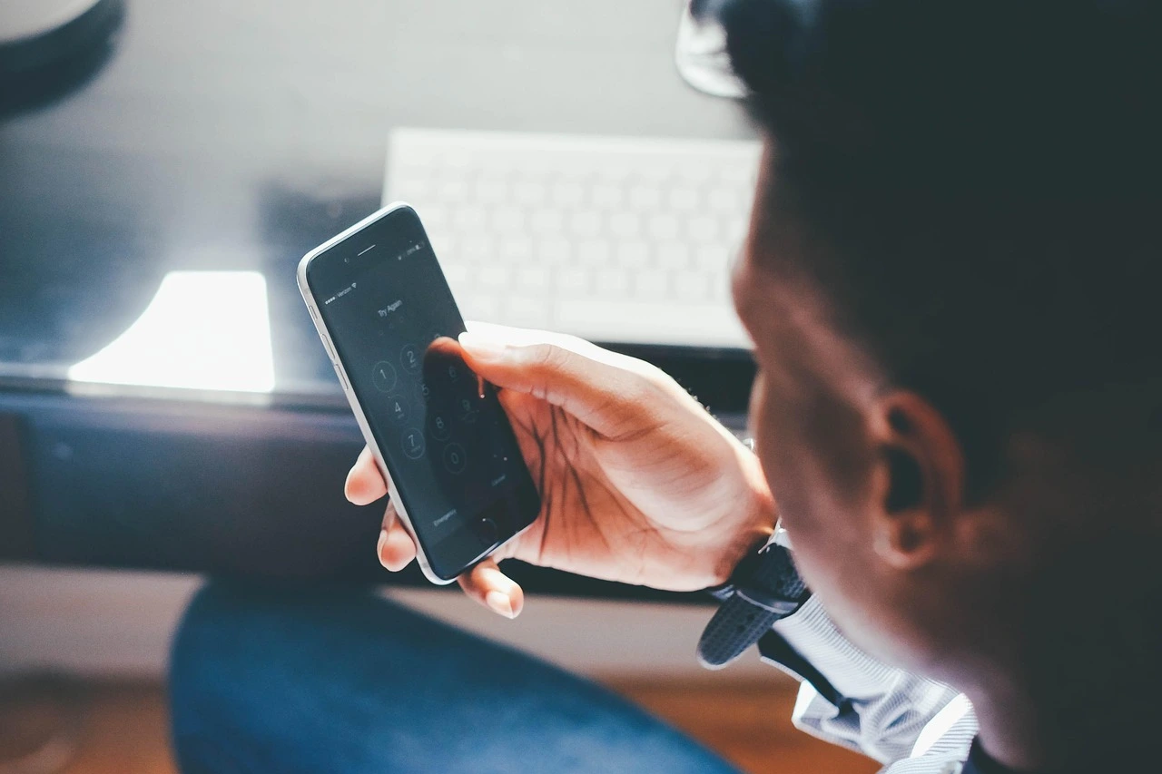 un homme prend son smartphone pour joindre le service client de la conciergerie Thomas Home Service