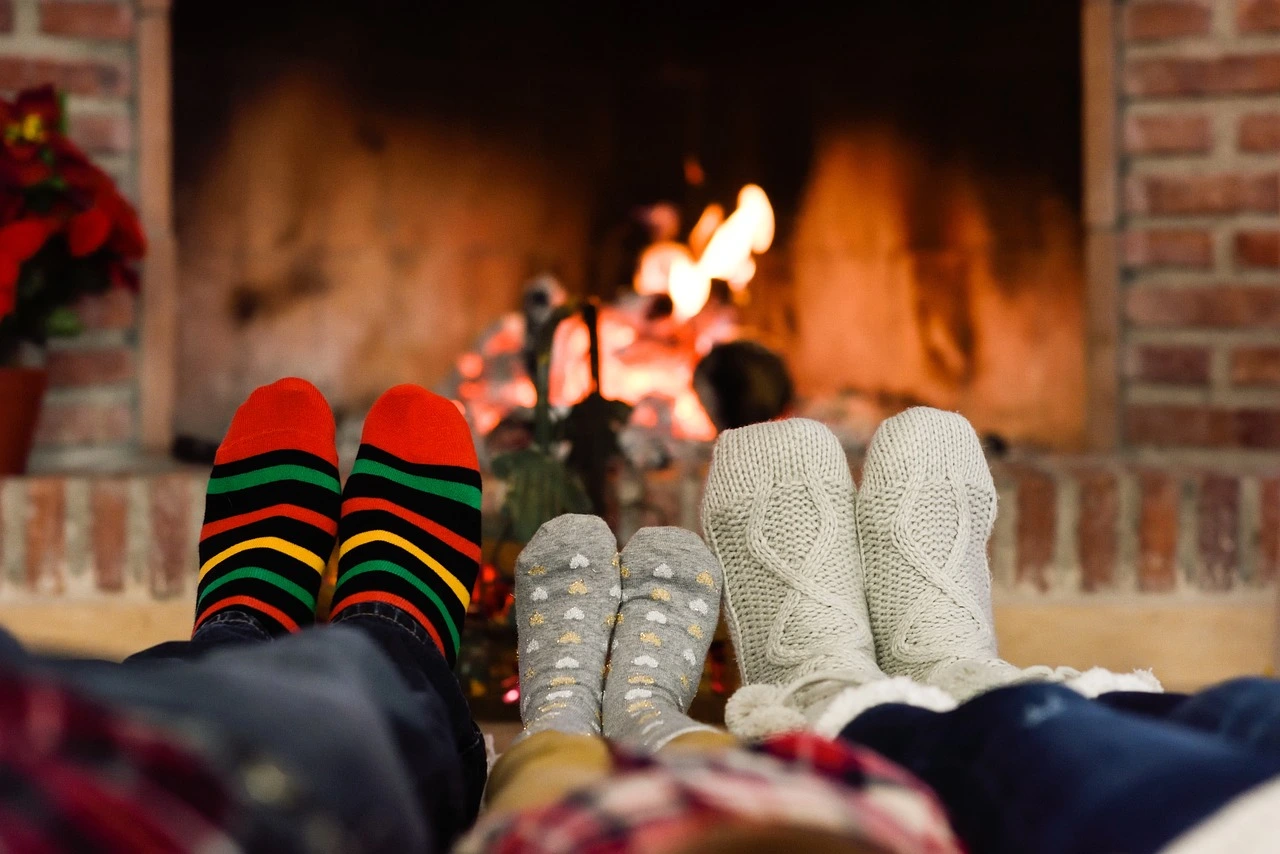 des pieds d'une famille qui se réchauffe auprès du feu de cheminée