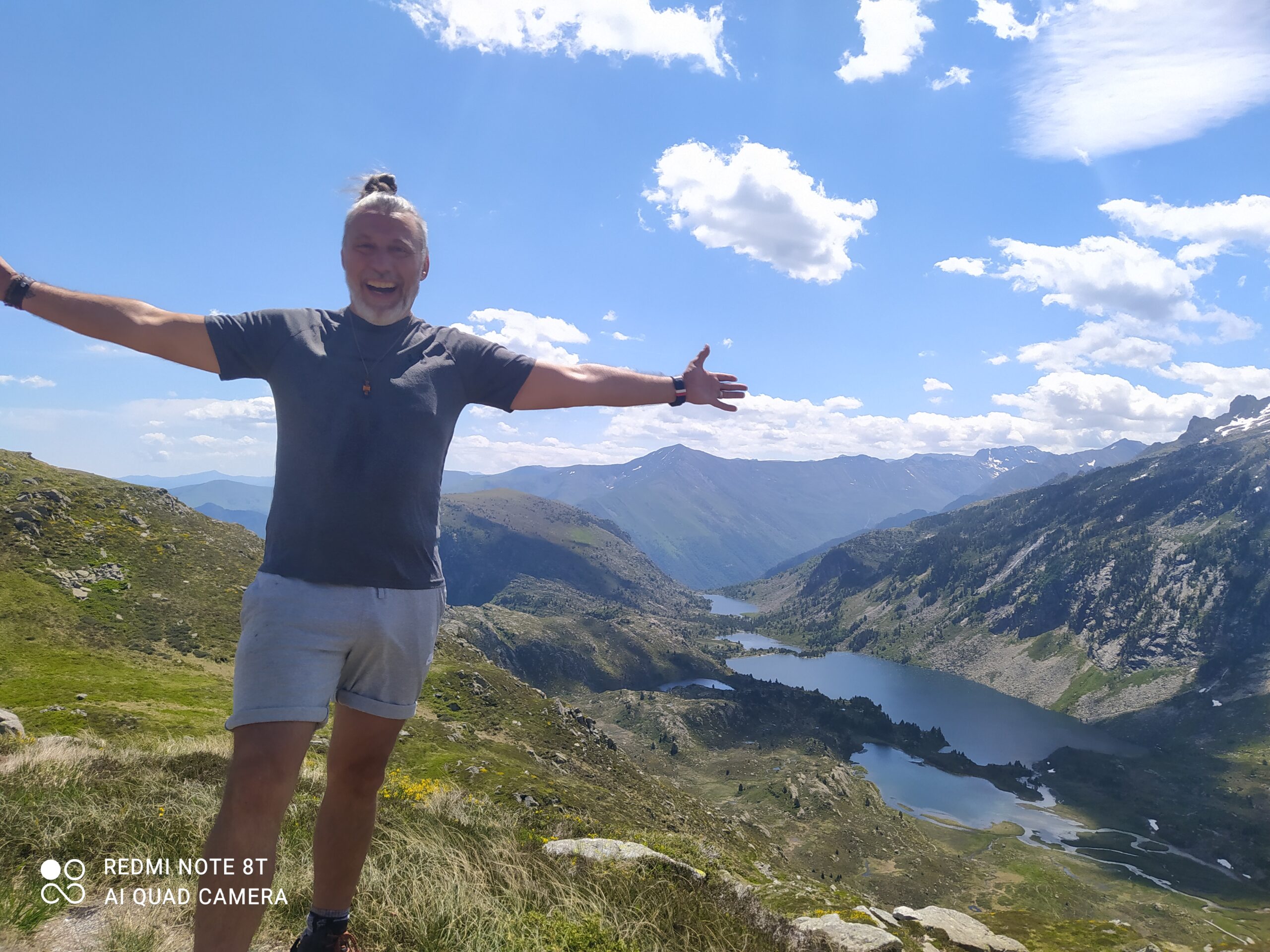 randonneur-été-couserans-lac-montagne homme bras ouverts au sommet des étangs de Bassies dans le Couserans